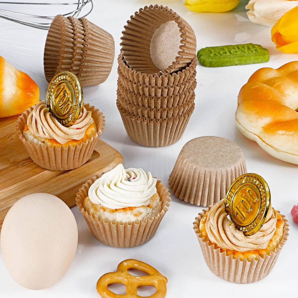 Brown paper cupcake liners with decorated cupcakes and baking ingredients on a white surface