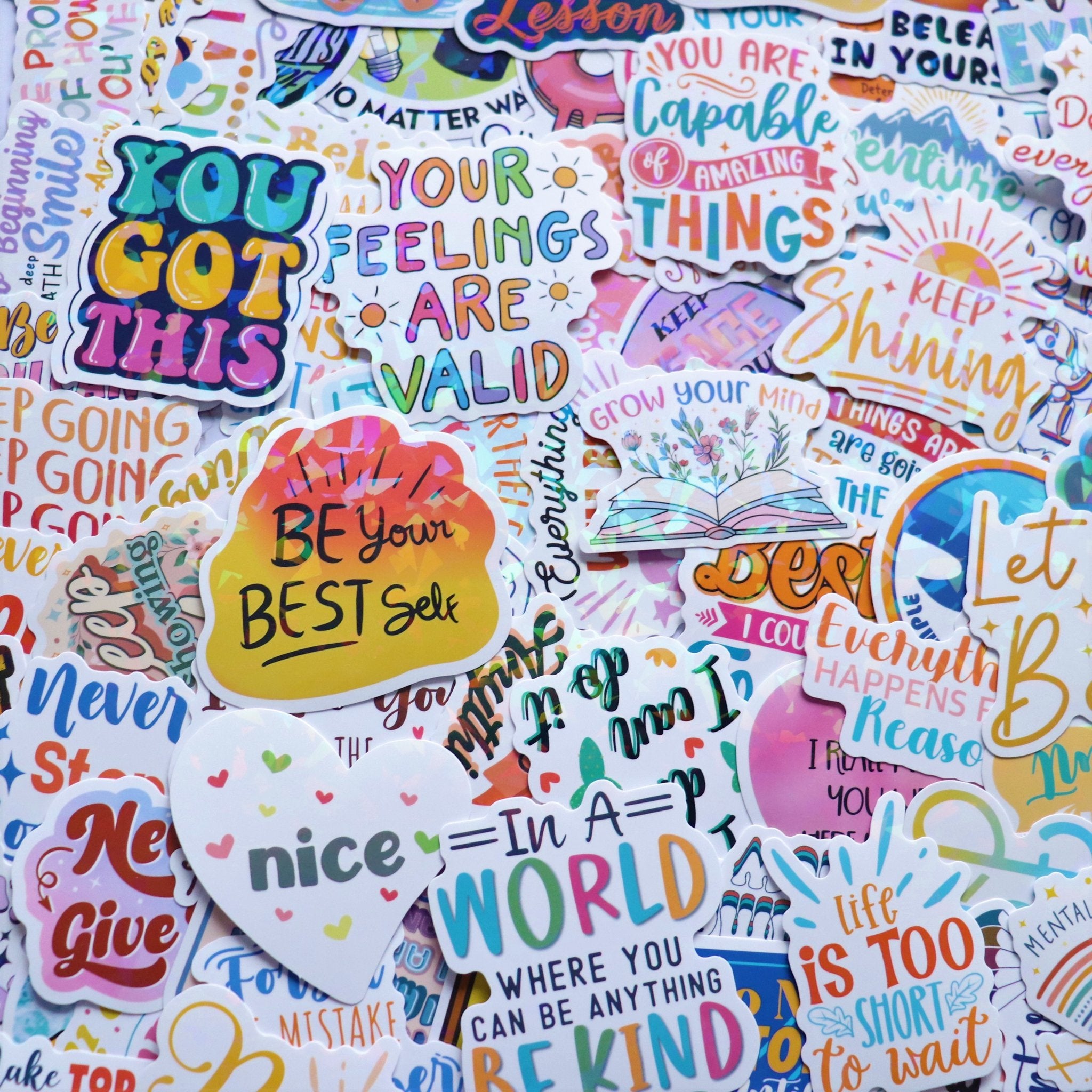 A collection of holographic affirmation stickers with motivational quotes and colorful designs.