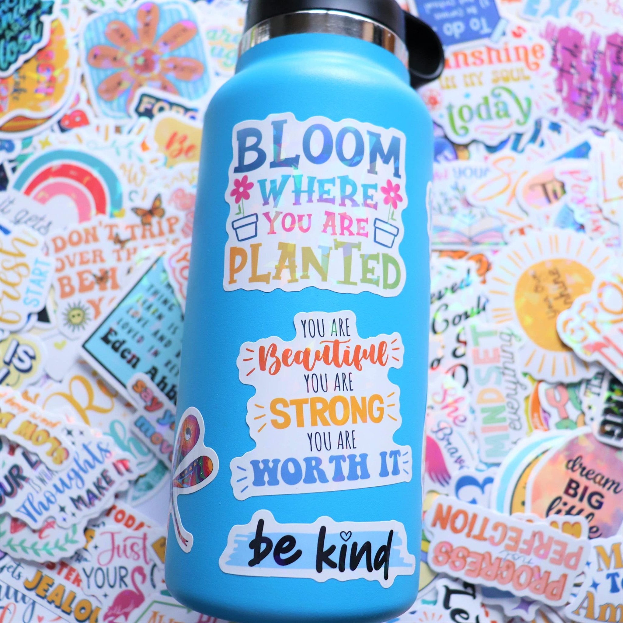 Blue water bottle covered in holographic affirmation stickers with motivational quotes and designs.