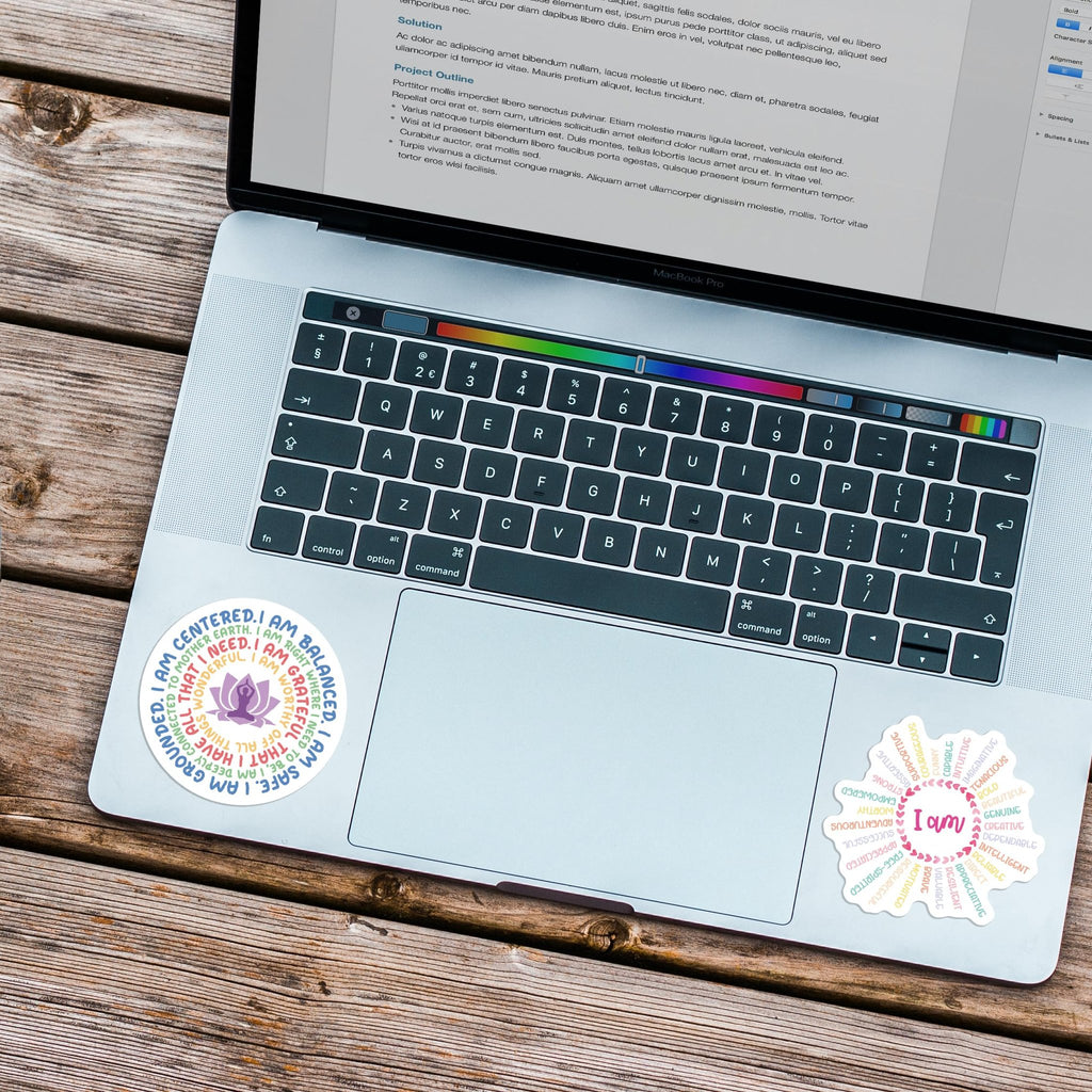Two round vinyl stickers with motivational quotes and lotus flower design on a laptop keyboard.