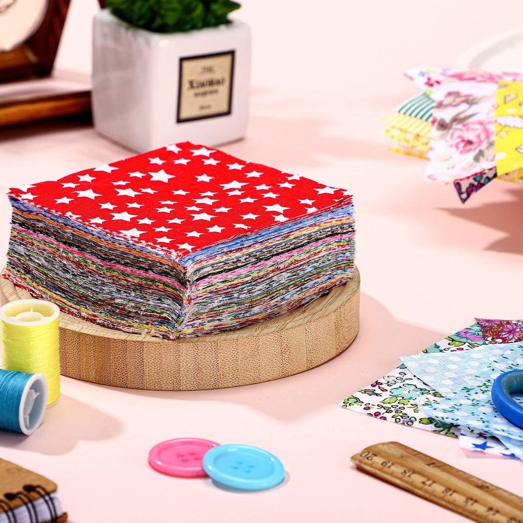 Stack of 4x4 inch fabric squares with red star pattern on top, surrounded by sewing supplies.