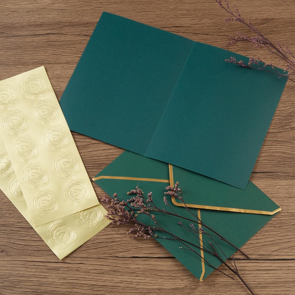 Embossed gold foil heart stickers with envelopes and a card on a wooden surface.