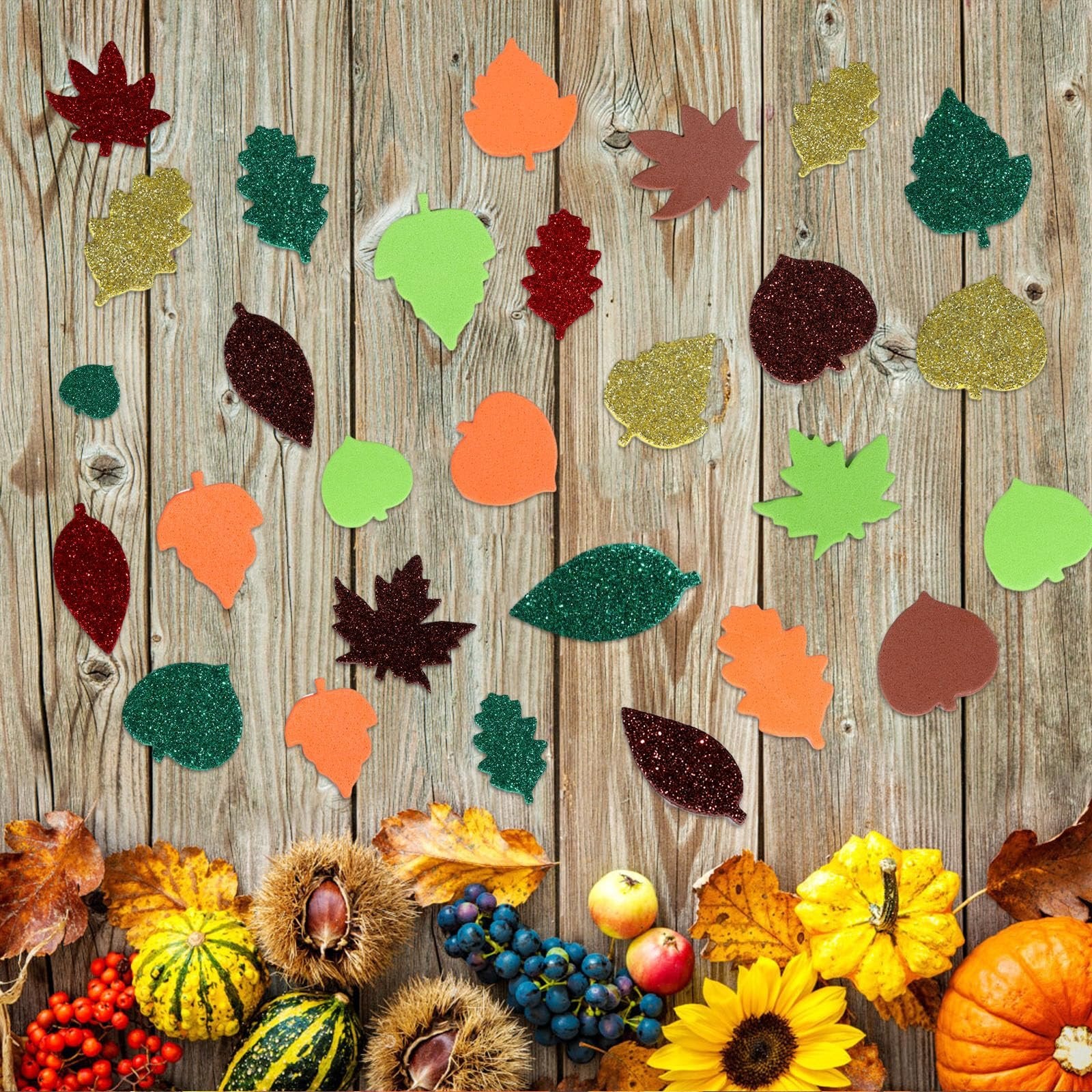 Assortment of fall leaf foam stickers scattered on a wooden background with autumn harvest decorations below.