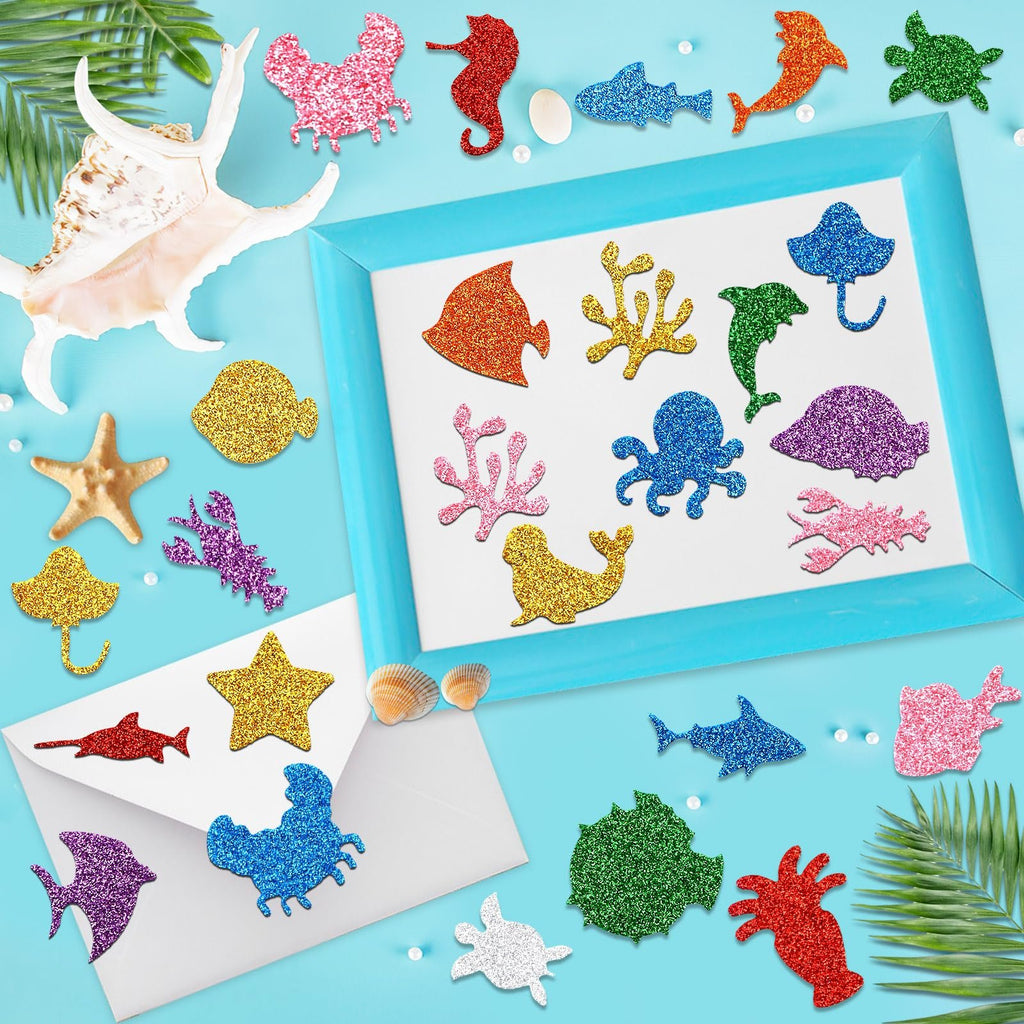 Glitter sea animal foam stickers arranged around a blue picture frame on a light blue background with shells and palm leaves.