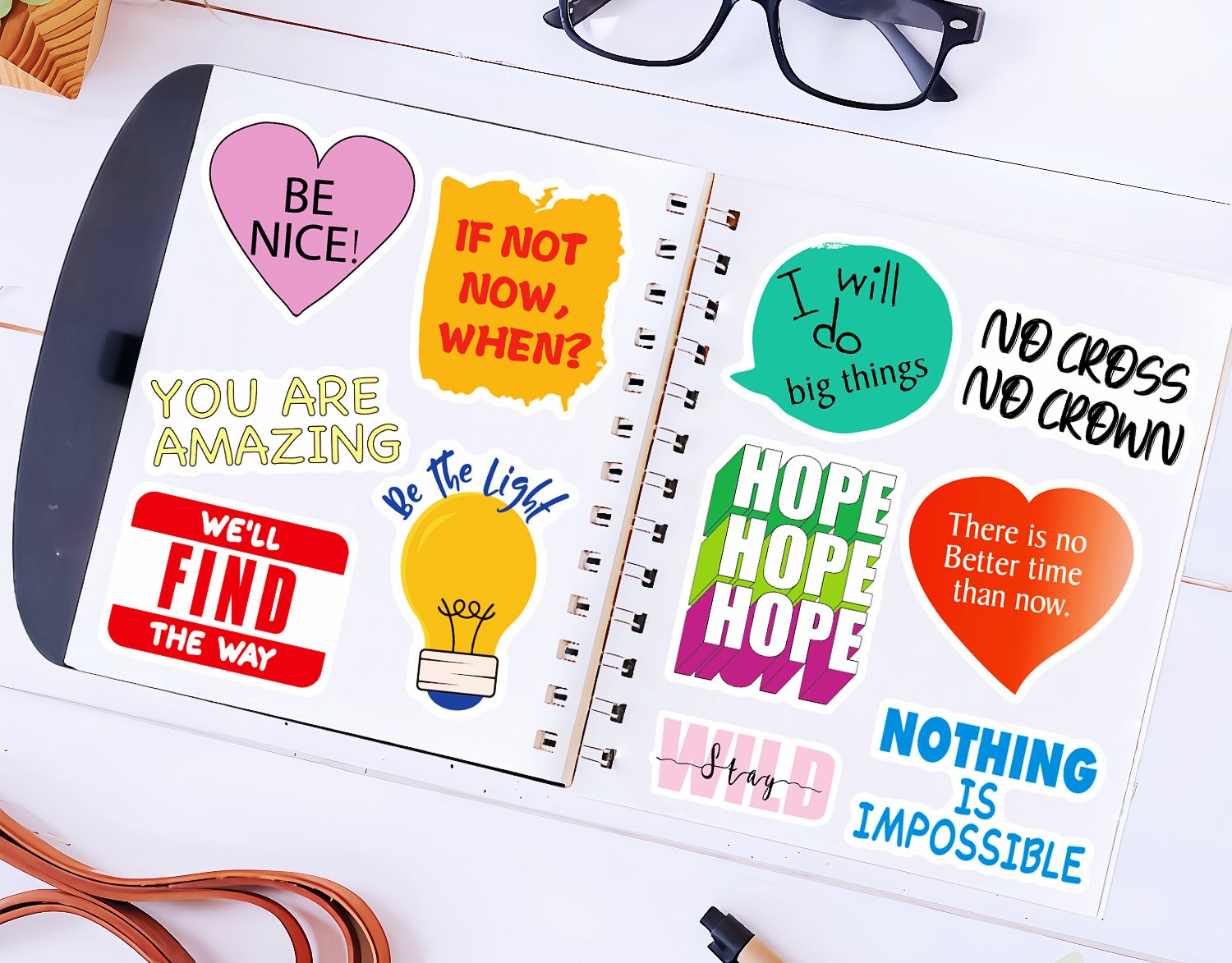 Assortment of inspirational quote stickers on an open notebook, including 'Be Nice!', 'If Not Now, When?', and 'You Are Amazing'.