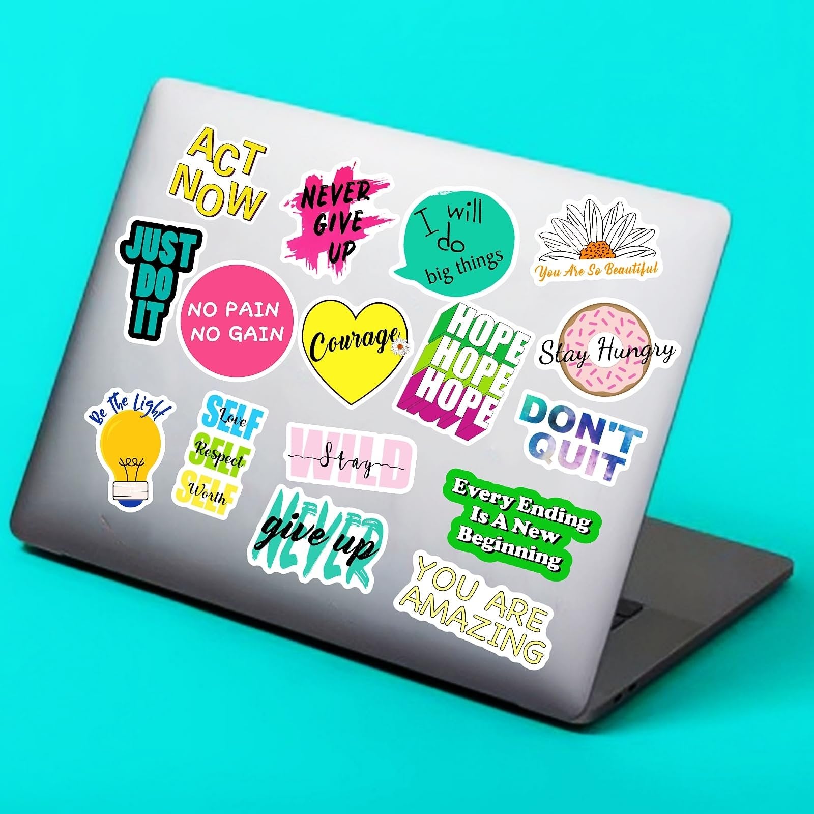Assortment of inspirational and motivational vinyl stickers applied to a laptop lid, featuring various quotes and designs.