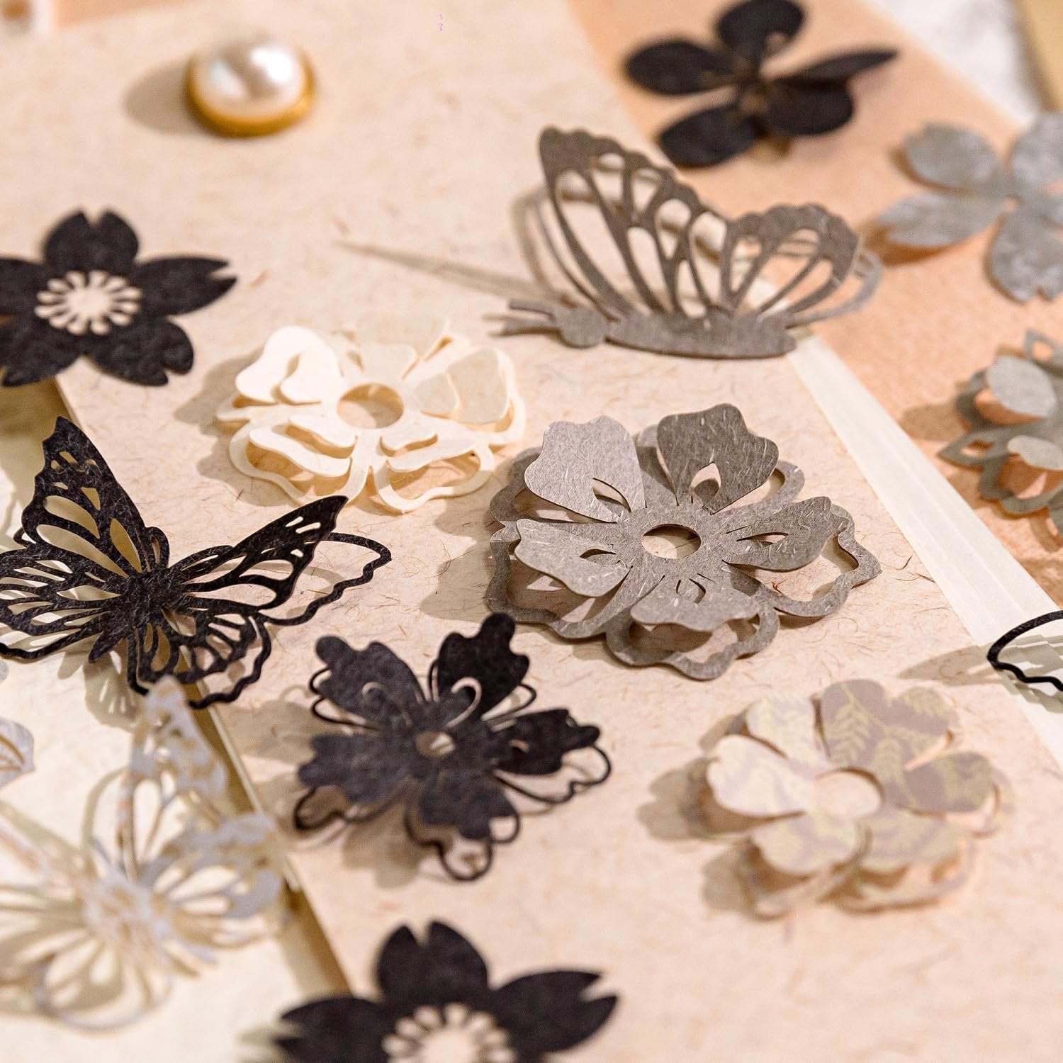 Assortment of paper craft cutouts including butterflies and flowers in black, gray, and cream.