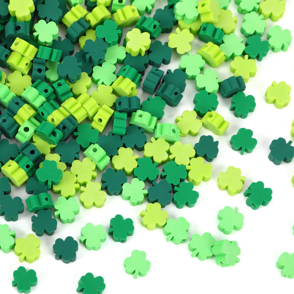 Pile of green shamrock polymer clay beads in four shades, some with holes for jewelry making.