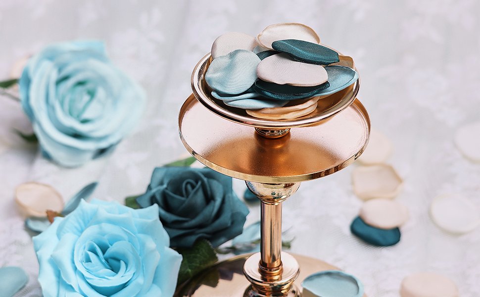 Close-up of silk rose petals in vintage green, champagne, and light blue colors, displayed on a gold tiered stand with artificial roses in the background.