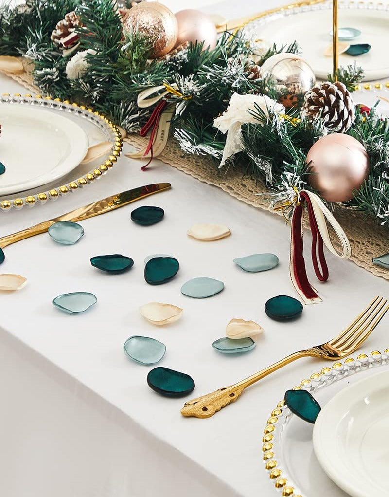 Table setting with scattered silk rose petals and a festive garland for a holiday event.