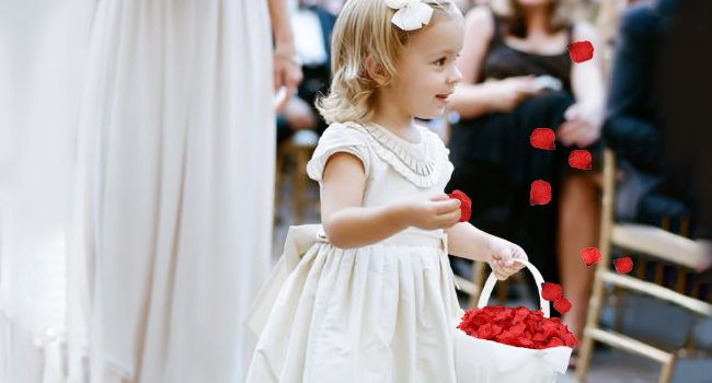 Flower girl holding a basket filled with dark red artificial rose petals at a wedding ceremony.