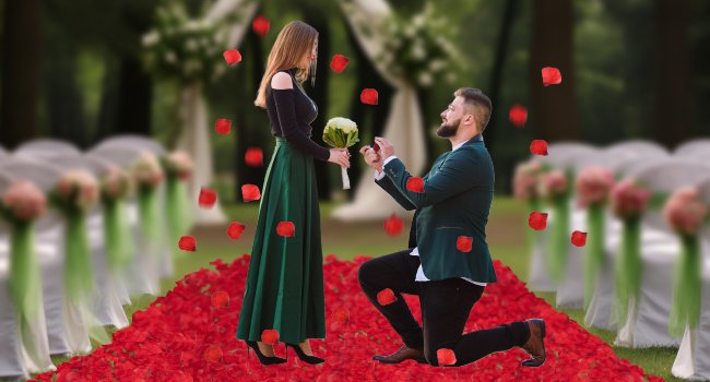 Man proposing to woman with rose petals scattered on wedding aisle