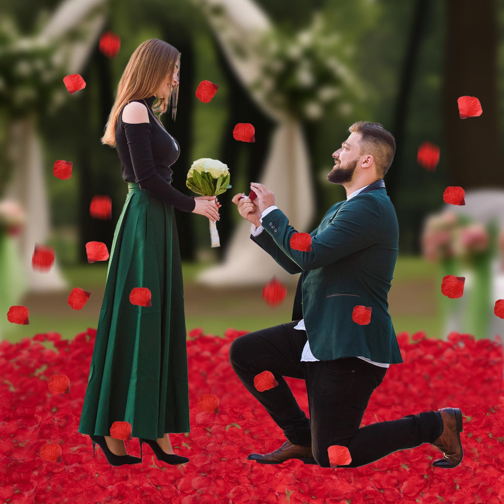 Man proposing to woman surrounded by red rose petals, with petals falling from above.