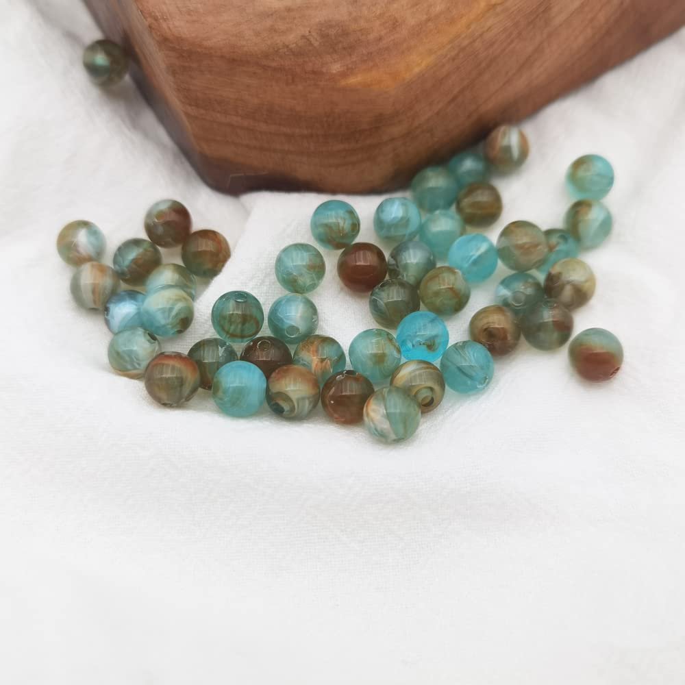 Scattered 8mm marble pattern acrylic beads in blue and brown tones on a white cloth with a wooden block.