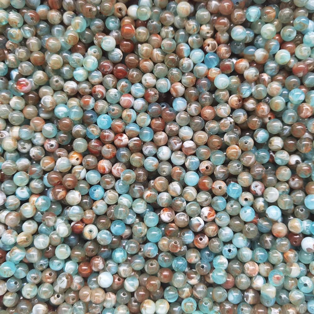 Close-up overhead view of a large pile of 8mm round acrylic beads with a marble pattern in blue, brown, and white.