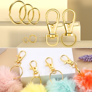 Gold keychain making kit components including jump rings, clasps, and lobster clasps, with colorful pom poms attached to some.