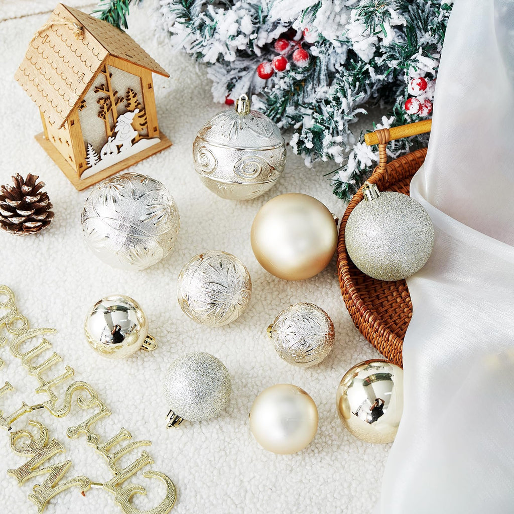 Assortment of shatterproof Christmas ball ornaments in various sizes and finishes, arranged with a wooden house, pinecone, and flocked tree branch.