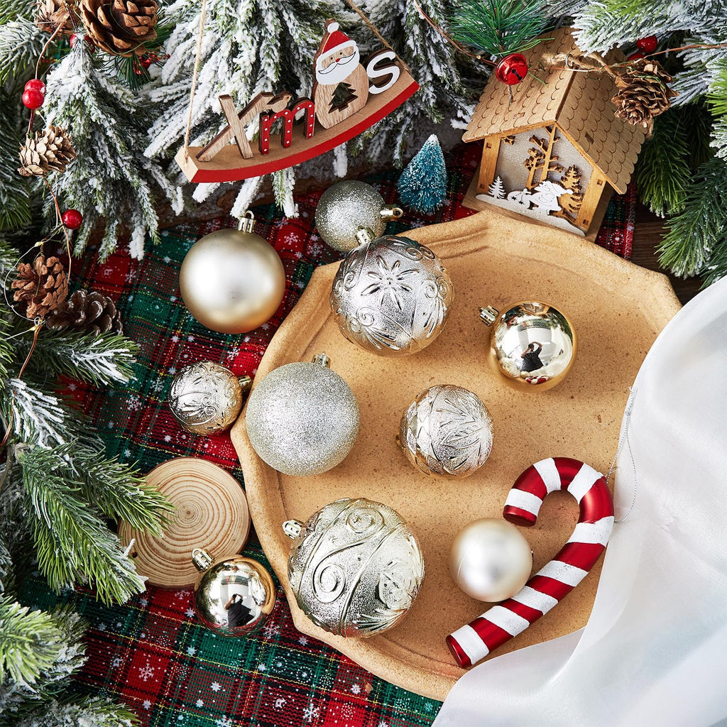Christmas ornaments including gold and silver balls, a candy cane, and wooden decorations on a plaid cloth with frosted evergreen branches.