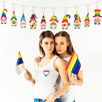 Two women holding rainbow flags in front of a string of rainbow gnome pride ornaments