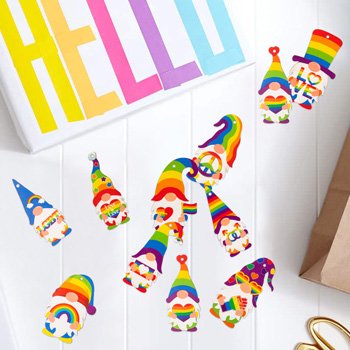 Rainbow gnome pride ornaments scattered on a white surface with a 'HELLO' banner and brown paper bag.