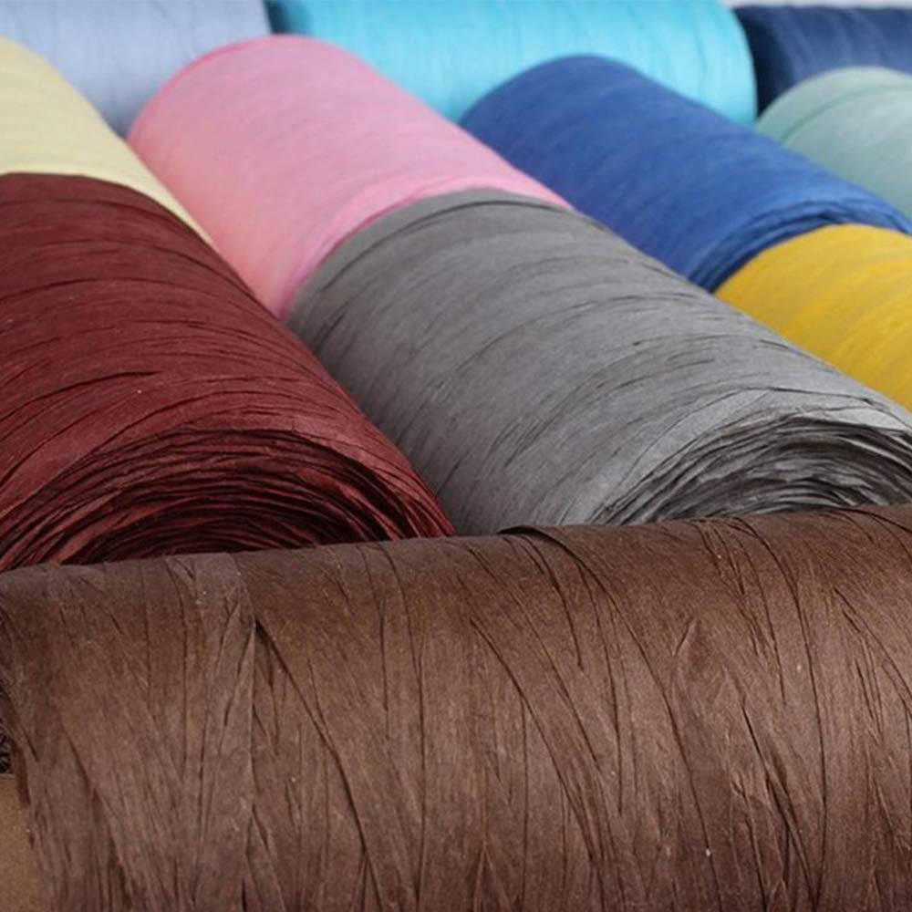 Close-up view of multiple spools of colorful raffia paper yarn in various shades including brown, maroon, gray, pink, blue, and yellow.
