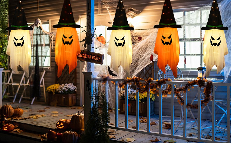 Five glowing ghost decorations with witch hats hanging on a porch for Halloween, with pumpkins and cobwebs.