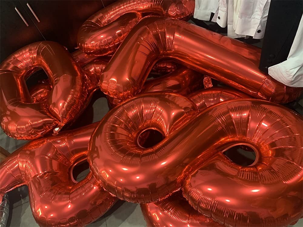 Pile of shiny red number balloons, including a 5 and an 8, for party decoration.