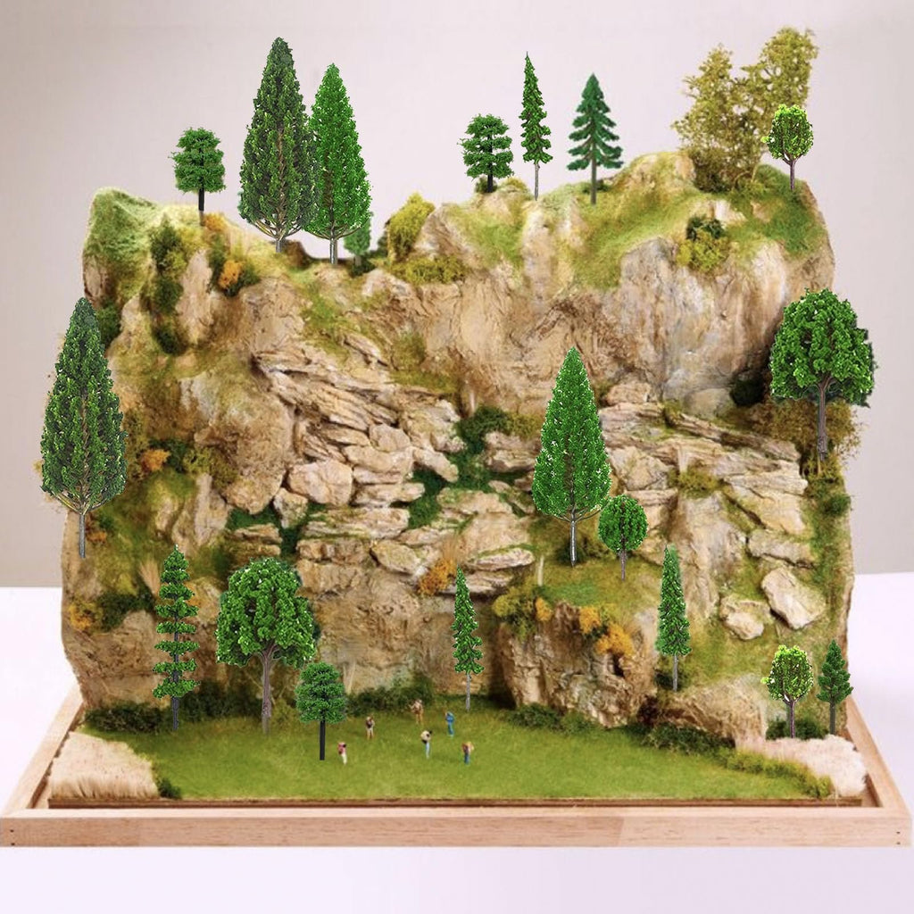 Diorama landscape with miniature trees and tiny figures on a rocky mountain base.
