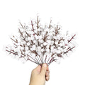 Hand holding a bunch of white berry stems with brown branches against a white background