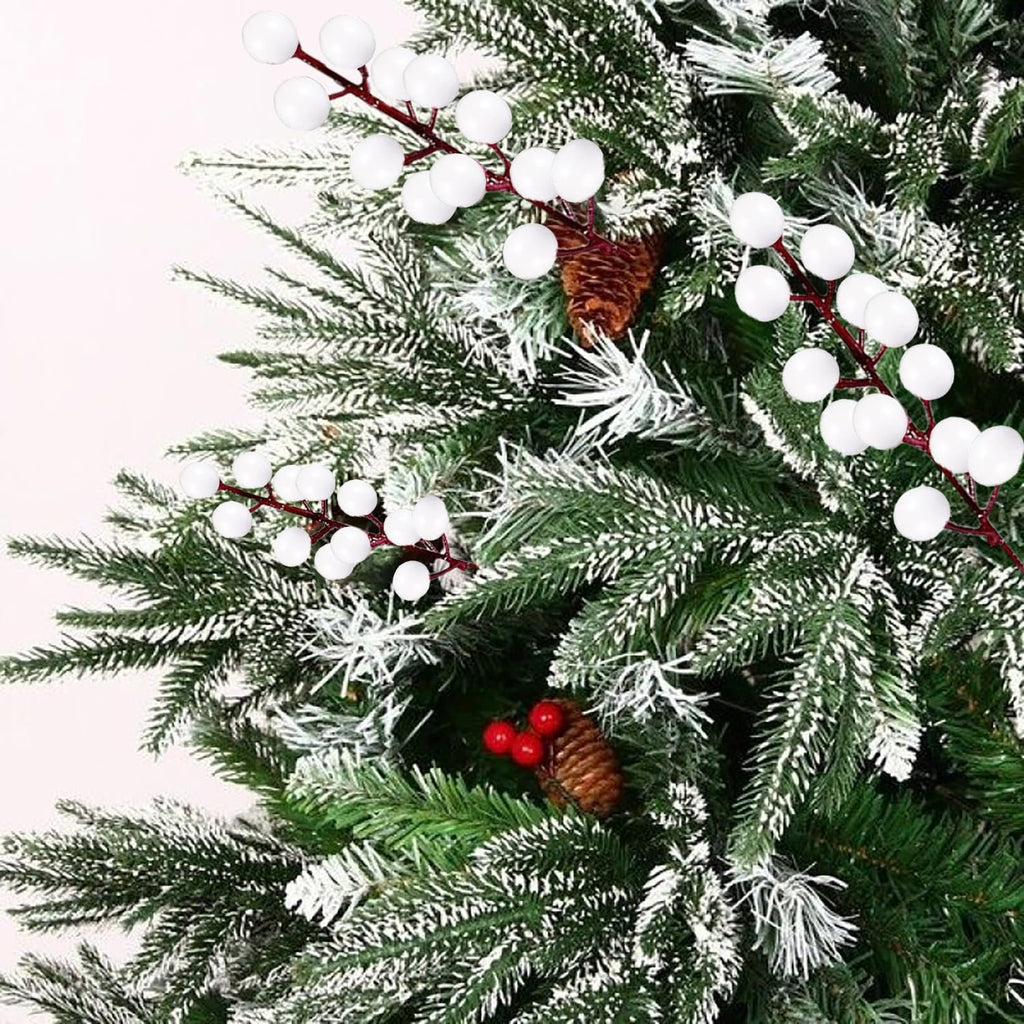 White berry stems with pine cones and red berries on a flocked Christmas tree branch