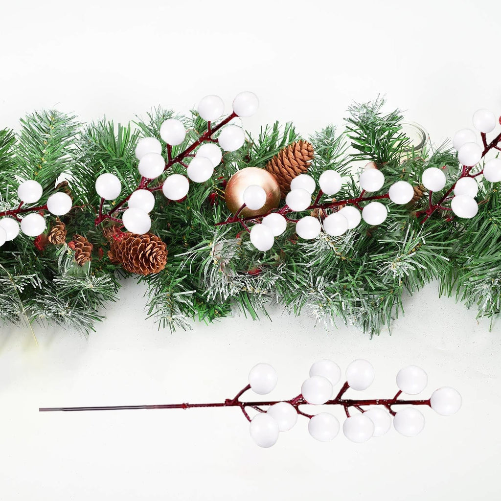 White berry stems and pine garland with pinecones and gold ornaments on a white background
