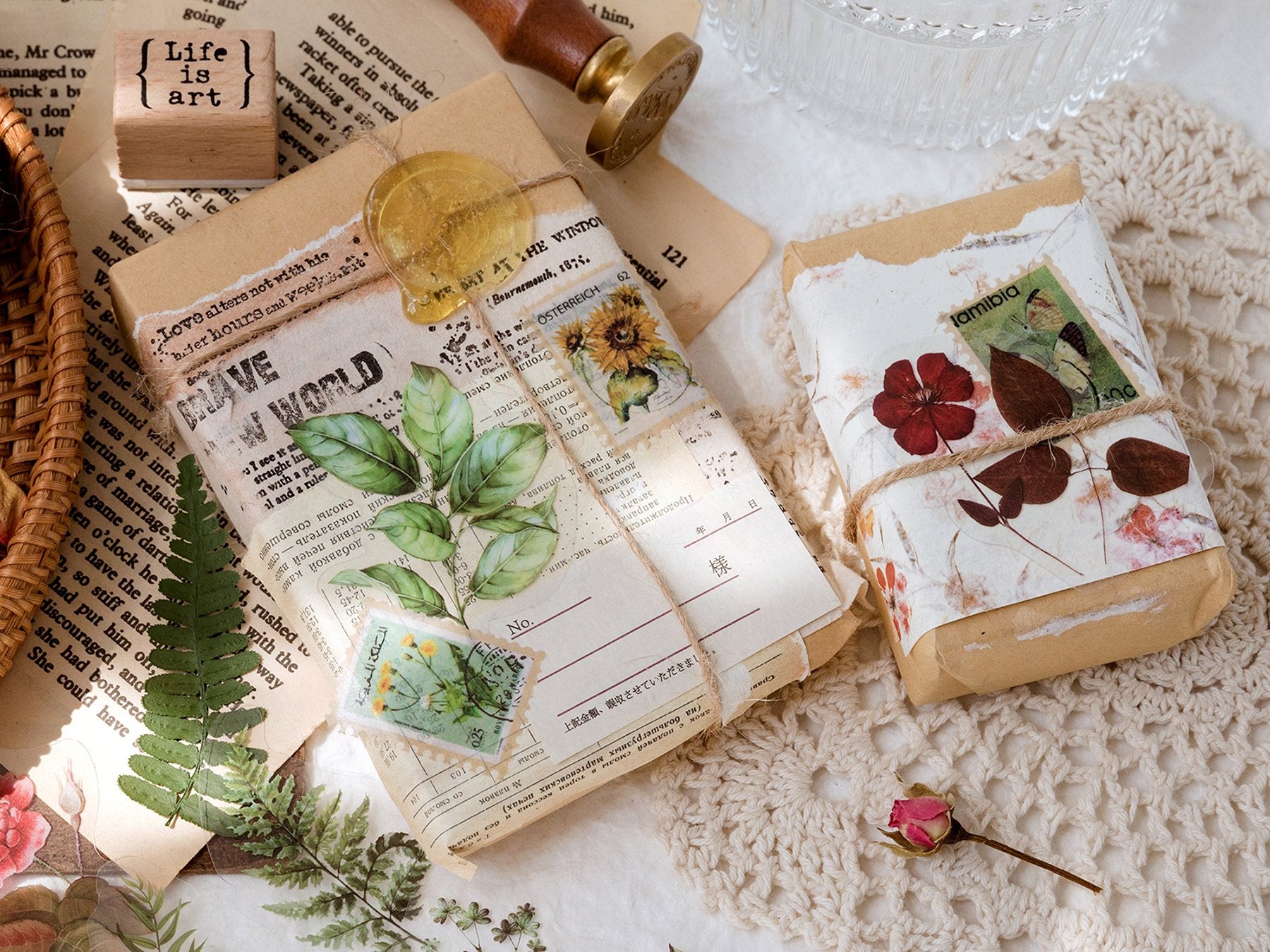 Flat lay of vintage-style craft supplies including wrapped gifts, old papers, stamps, and botanical stickers.