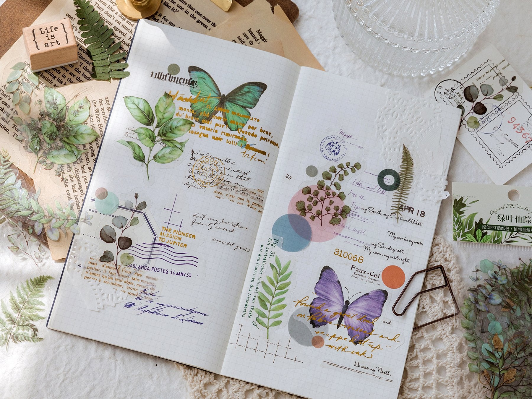 Journal spread with botanical stickers of butterflies, leaves, and flowers, plus decorative text and stamps.