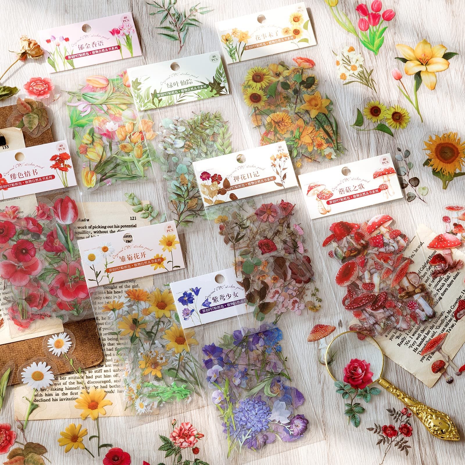 Assortment of clear PET botanical stickers featuring flowers, leaves, and mushrooms, scattered on a wooden surface with vintage book pages.