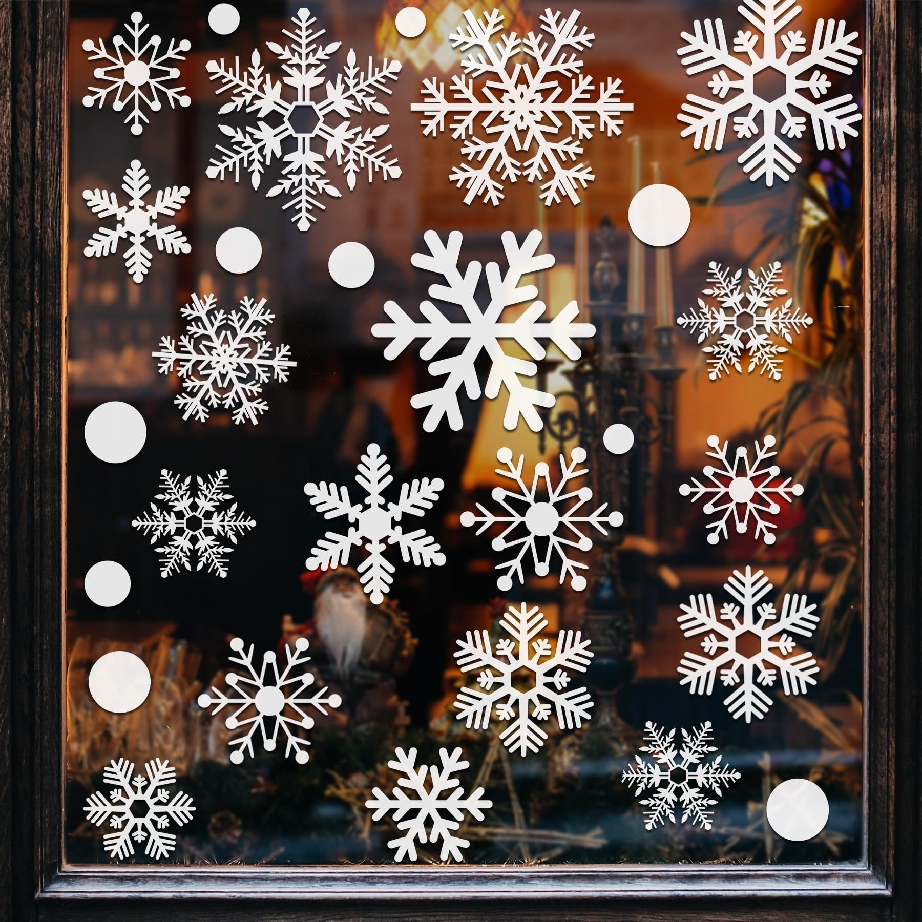White snowflake window decals applied to a glass window with a dark wooden frame, showing various snowflake designs and some solid circles.