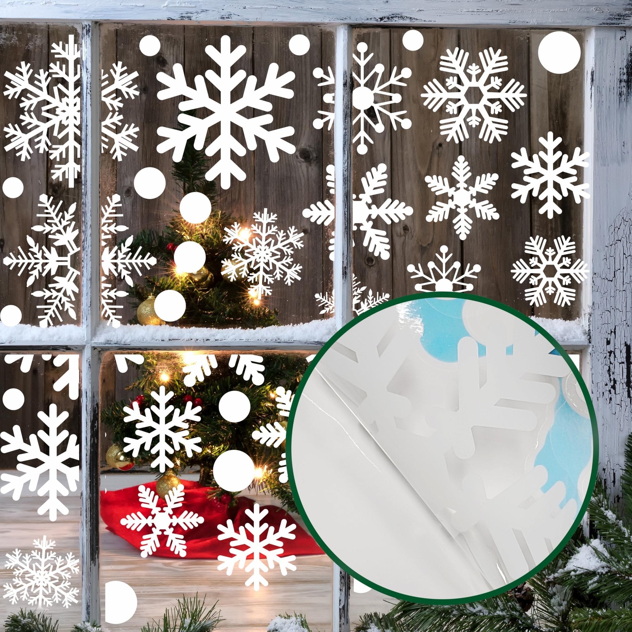 Christmas window decals with snowflakes and circles applied to a rustic wooden window frame with a decorated Christmas tree visible inside.