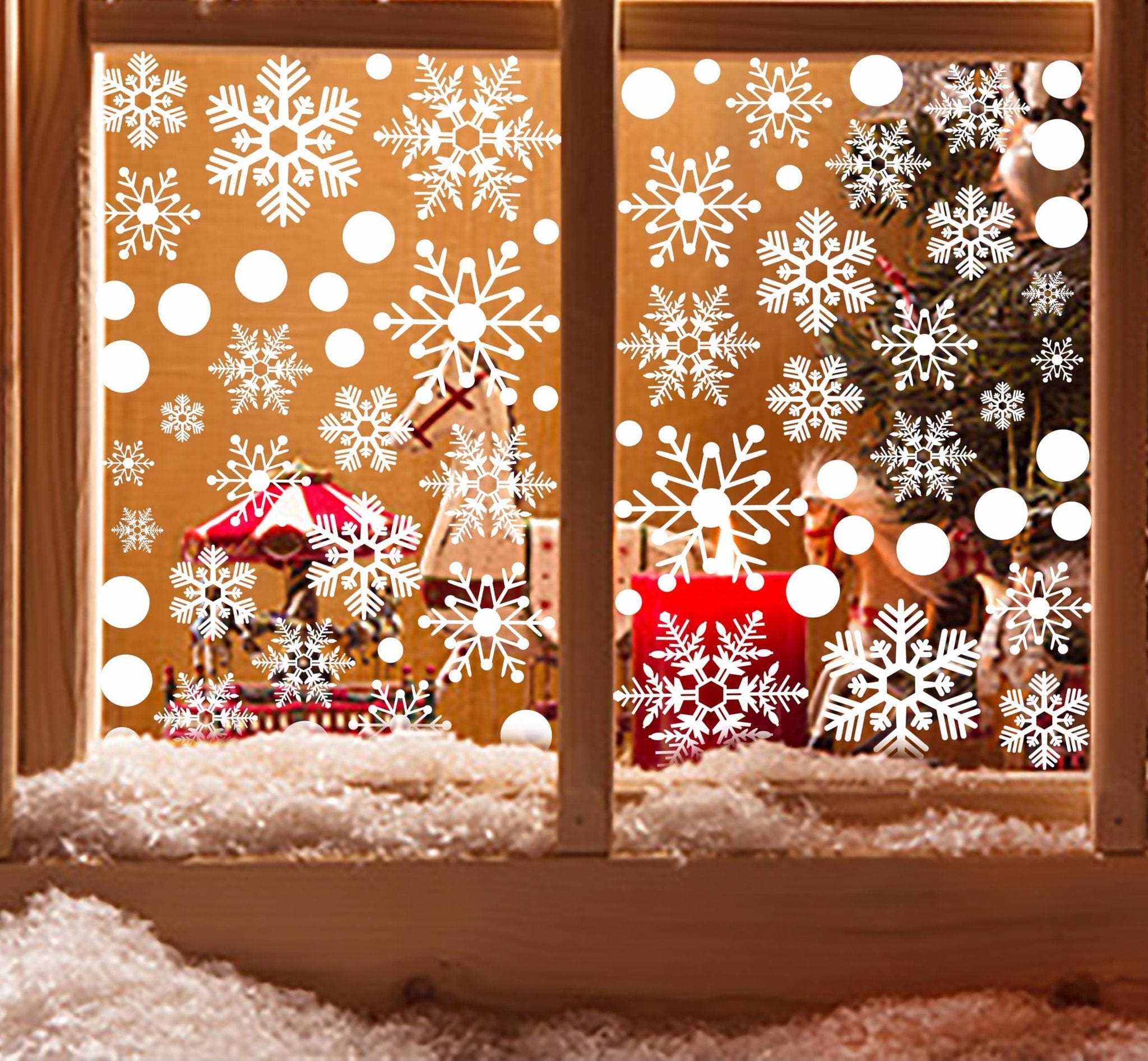 Christmas window decals with snowflakes and circles applied to a window with a festive scene behind it.