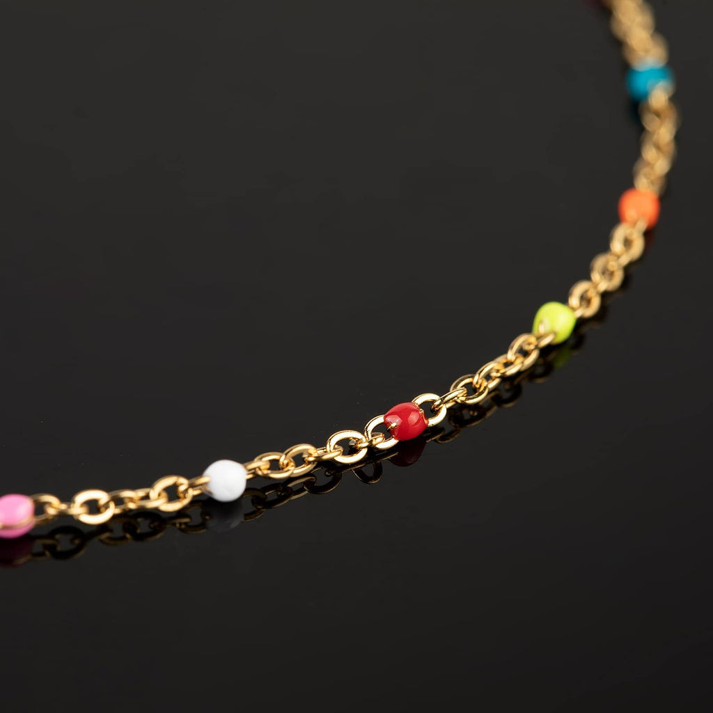 Gold-plated stainless steel chain with colorful beads on a black reflective surface