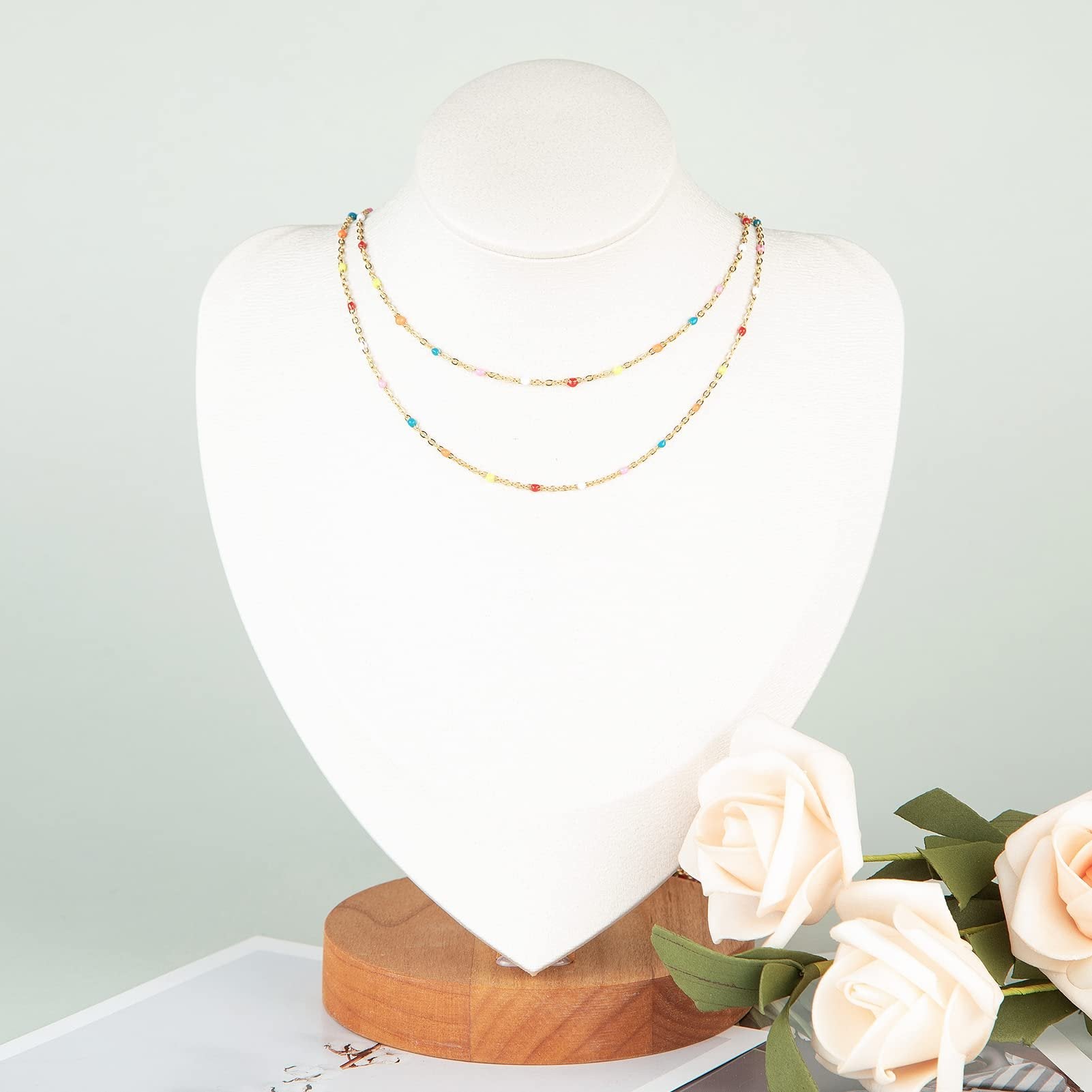Gold-plated stainless steel beaded necklace with colorful beads displayed on a white bust form with faux roses.