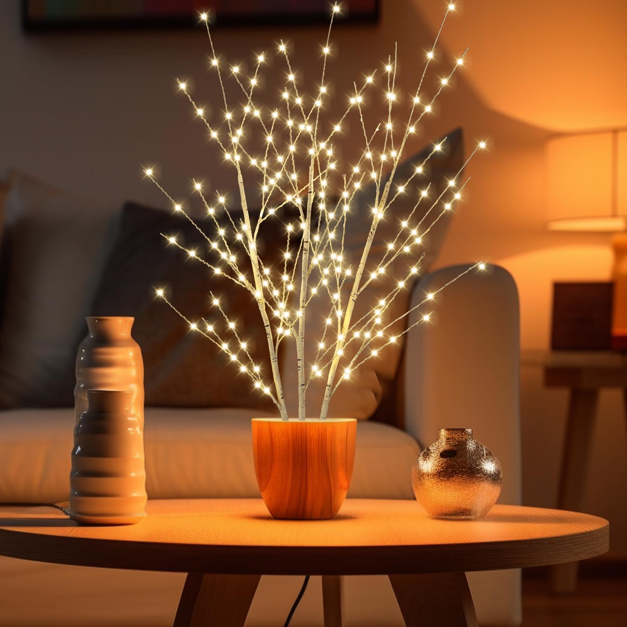 Illuminated birch tree with 180 LED lights in a wooden pot on a table with decorative vases.