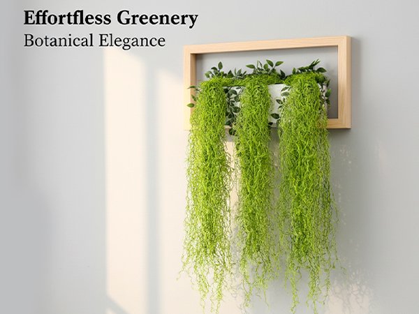 Three strands of artificial Spanish moss greenery hanging from a white planter inside a wooden frame on a wall.
