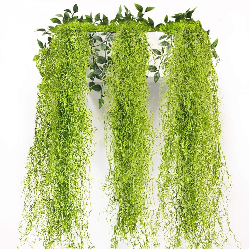 Three strands of artificial Spanish moss garland hanging against a white background with green leaves at the top.