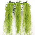Three strands of artificial Spanish moss garland hanging against a white background with green leaves at the top.