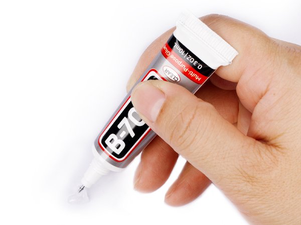 Hand holding a tube of clear multi-purpose glue with B-7000 label