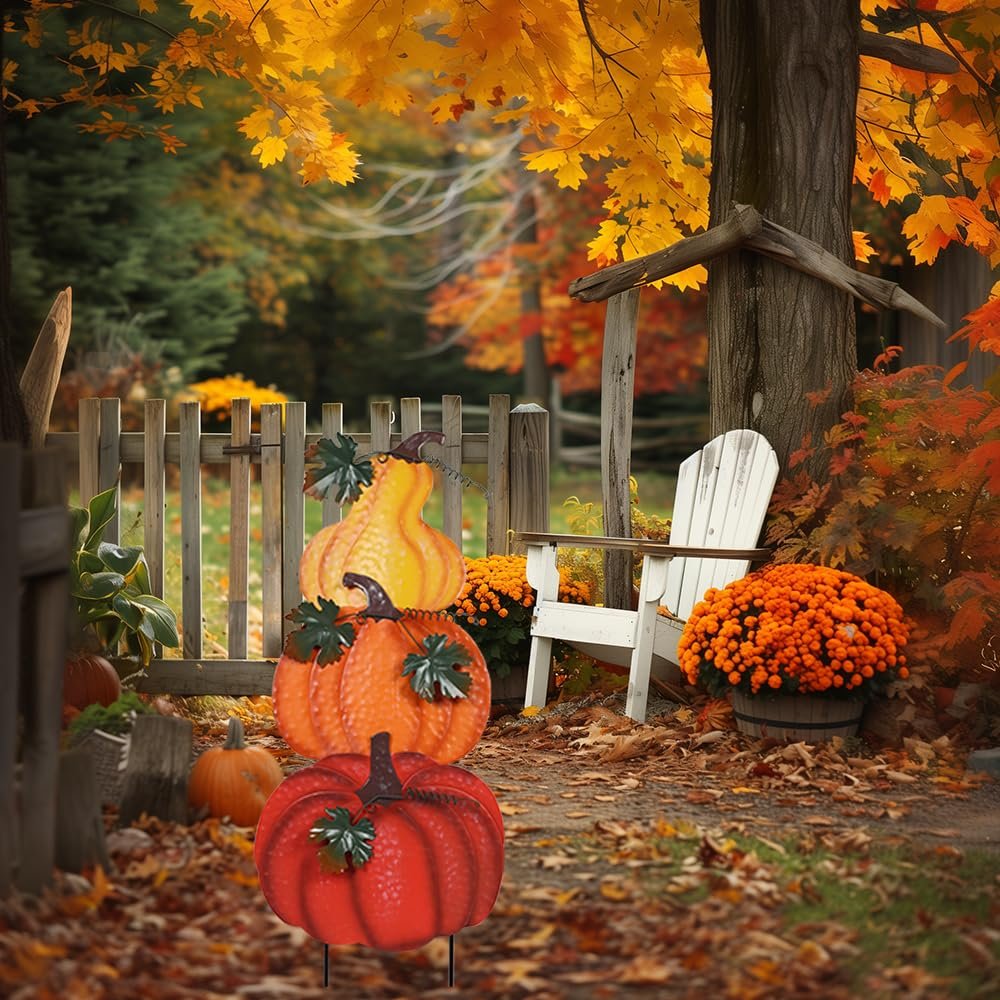 Stacked hand-painted metal pumpkins garden stake with wind-moving leaves in a fall outdoor setting.
