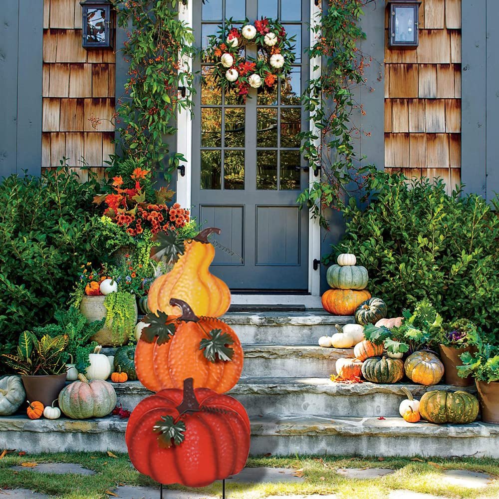 Stacked hand-painted pumpkins garden stake with wind-moving leaves on a porch with fall decor