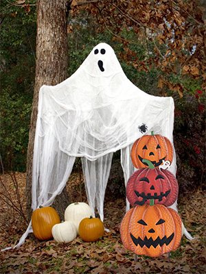 Stackable Halloween pumpkin garden stakes with a ghost decoration in a wooded setting