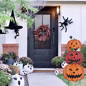 Stackable metal pumpkin garden stakes with Halloween decorations on a porch.