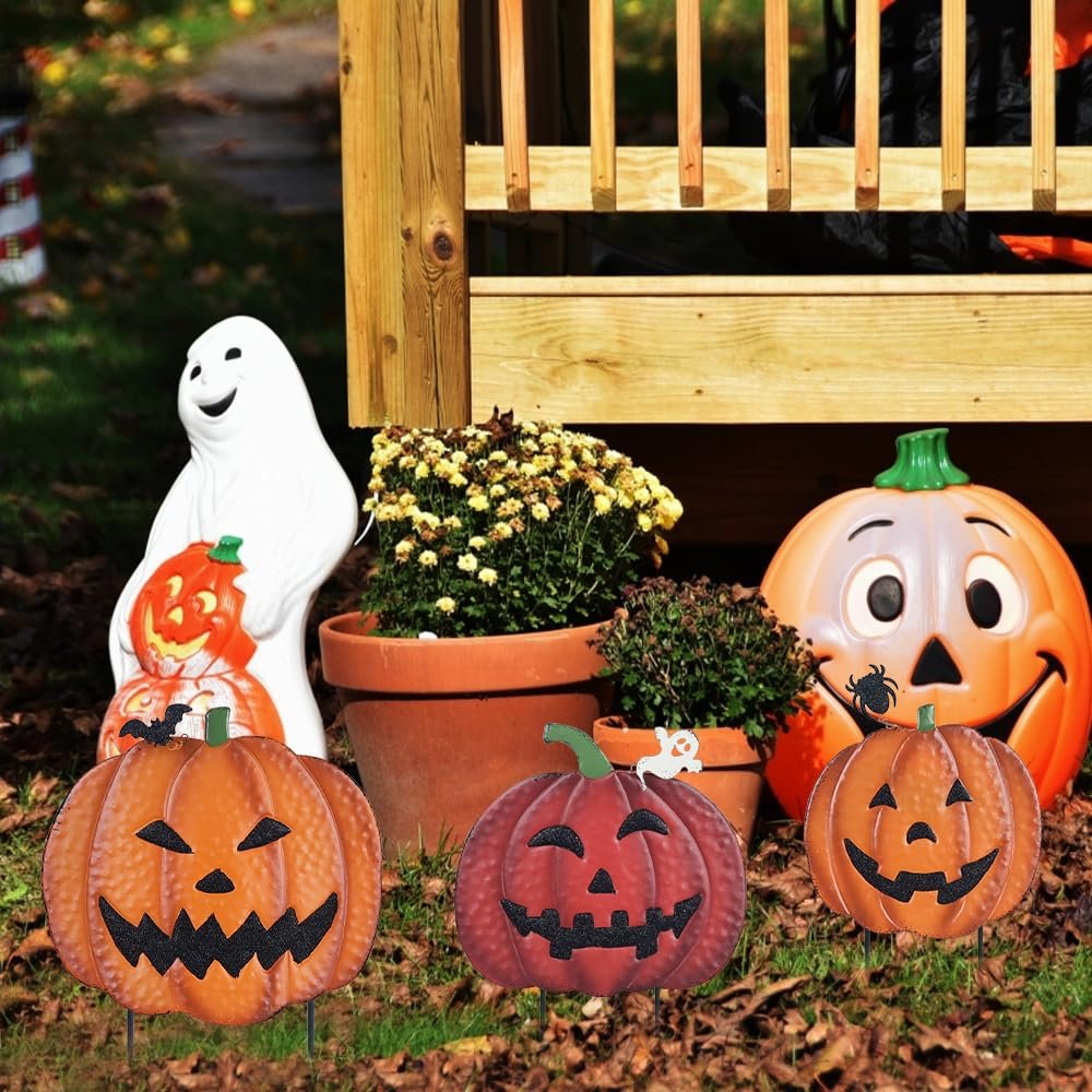 Halloween garden decorations including three jack-o'-lantern stakes, a ghost figure, and a large pumpkin decoration on a wooden deck.