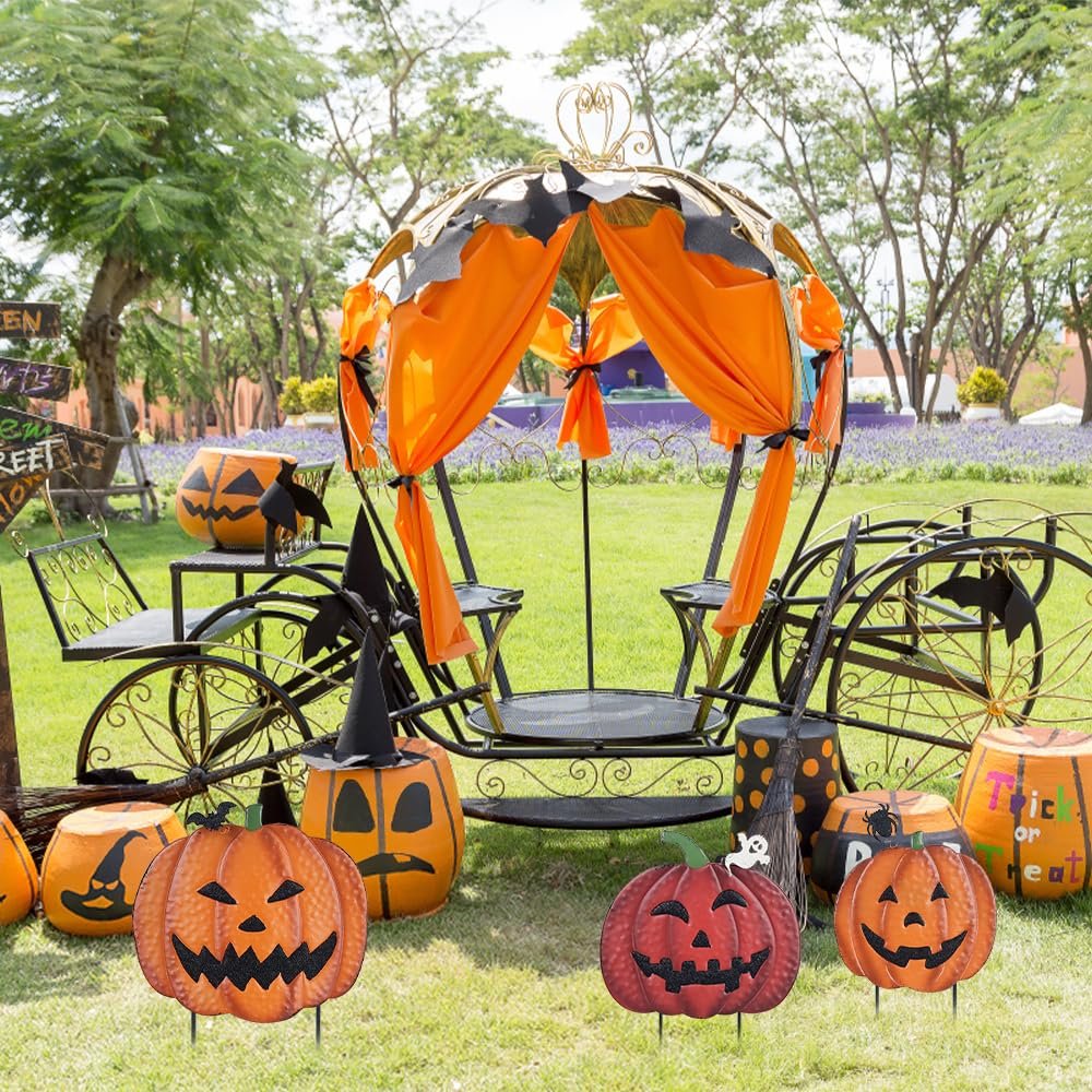 Halloween pumpkin garden stakes and a decorative carriage set up on a lawn with trees and flowers in the background.